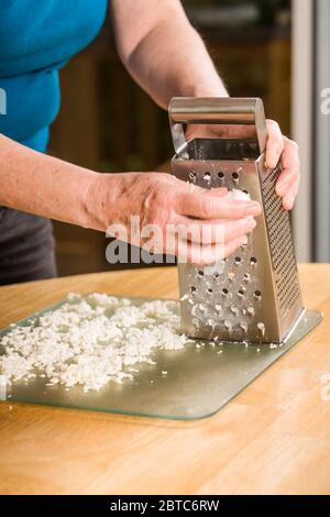 Frau Reibe Mozzarella Käse wird verteilt, um zu trocknen, bevor sie als Pizza Belag verwendet Stockfoto