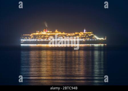 Weymouth, Dorset, Großbritannien. Mai 2020. Das leere Cunard-Kreuzfahrtschiff Queen Victoria, das jetzt vor der Küste von Weymouth in Dorset während der Kreuzfahrt-Abschaltung wegen der Sperrung der Coronavirus-Pandemie verankert ist, wird bei Einfall der Nacht beleuchtet. Bild: Graham Hunt/Alamy Live News Stockfoto