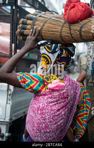 Frau mit Besen auf dem Kopf und Baby auf dem Rücken in Mombasa Stockfoto