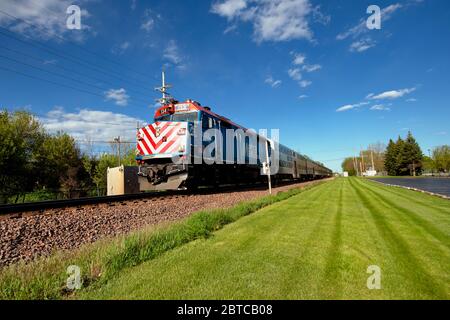 Genf, Illinois, USA. Eine Metra Lokomotive schiebt ihren Pendlerzug nach Chicago vor der Ankunft am Depot in Genf, Illinois. Stockfoto