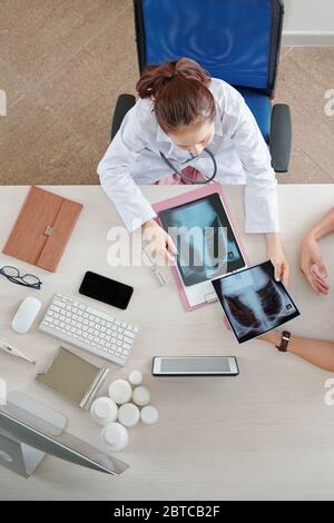 Arzt prüft Röntgenaufnahmen des Patienten mit Lungenentzündung, Ansicht von oben Stockfoto