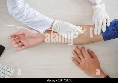 Patient mit Infusionstherapie im Krankenhaus, Krankenschwester mit Venenkatheter in Armvene Stockfoto