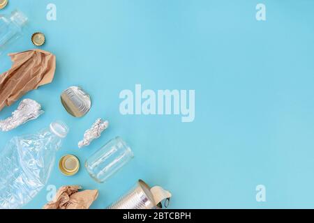 Recycelbarer verschiedener Müll bestehend aus Papier, Glas, Metall, Kunststoff auf blauem Hintergrund. Abfalltrennungskonzept. Flatlay, Kopierplatz. Stockfoto