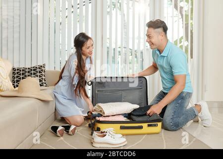 Lächelnd schön asiatisch Freund und Freundin Verpackung großen Koffer für die Reise Stockfoto