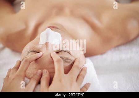 Mann mit Nasenstreifen bekommen Anti-Aging und erfrischende Gesichtsmassage im Schönheitssalon Stockfoto