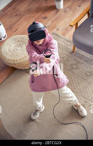 Teen Mädchen tragen VR Brille spielen Virtual Reality Spiel schießen an der Kamera von oben. Stockfoto