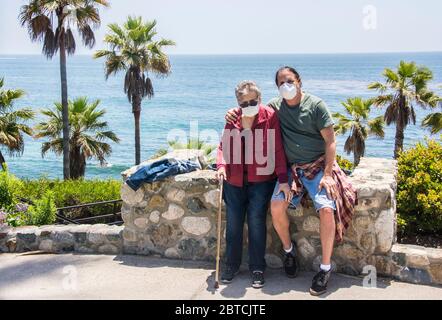 Eine Mutter von 83 Jahren mit ihrem 57-jährigen Sohn, beide maskiert, auf einem Spaziergang in Laguna Beach, Kalifornien, USA. Stockfoto