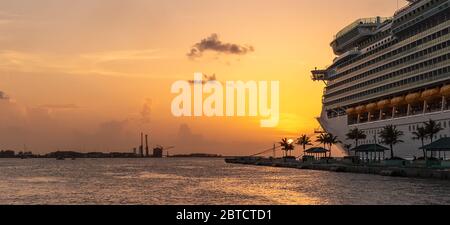 Luxuriöses Kreuzfahrtschiff bei Sonnenuntergang in Nassau, Bahamas angedockt. Goldene Stunde. Wunderschöner orange-gelber Sonnenuntergang. Reisekonzept. Stockfoto