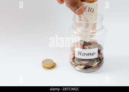 Hand fallen Währung Note in Pennies speichern Jar in Richtung Home Einzahlung sparen Stockfoto