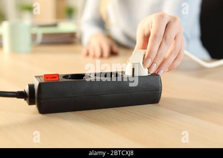 Nahaufnahme einer Frau, die zu Hause einen Stecker an eine Steckdosenleiste ansteckt Stockfoto