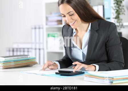 Glücklich Buchhalter Frau Berechnung auf Rechner prüft Dokument sitzt auf einem Schreibtisch im Büro Stockfoto