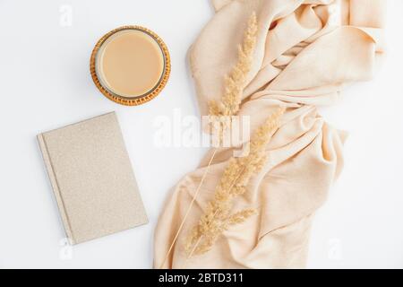 Flach legen Herbst Zusammensetzung. Von oben beige Decke, Tasse Kaffee, Papier Notizbuch und trockene Blumen auf weißem Tisch. Gemütlicher Schreibtisch im Boho-Stil. Stockfoto