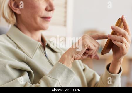 Nahaufnahme einer älteren Frau mit kurzen blonden Haaren, die das Mobiltelefon hält und eine Nachricht darauf eintippt Stockfoto