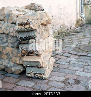 Trockenes Feuerholz in einem Gitter, in einem Haufen gestapelt, liegen auf der Straße der antiken Stadt, in der Nähe der Mauer. Stockfoto