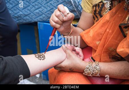 Künstler, die Henna-Tätowierung auf Frauenhände auftragen. Mehndi ist traditionelle indische dekorative Kunst Stockfoto