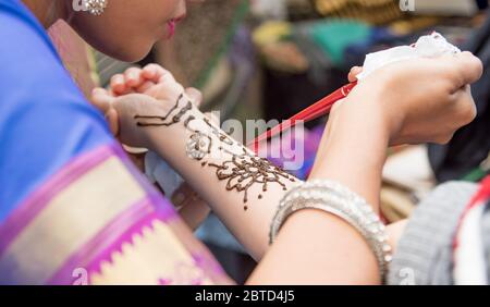 Künstler, die Henna-Tätowierung auf Frauenhände auftragen. Mehndi ist traditionelle indische dekorative Kunst Stockfoto