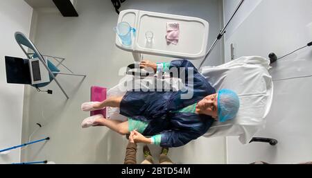 Overhead-Ansicht der auf dem medizinischen Stuhl Senior männlich im modernen Krankenhaus Frankreich Ruhe nach der Infektion Virus Coronavirus - Mann hält Hand seinen Vater. Stockfoto