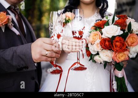 Die Braut und Bräutigam mit einem Hochzeitsstrauß, mit Gläsern Champagner stehend auf Hochzeitszeremonie unter dem Bogen mit Blumen und greene geschmückt Stockfoto