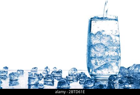 Gießen von Wasser in Glas mit Eis isoliert auf weißem Hintergrund Stockfoto