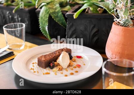 Servierteich aus Schokolade und Eis, garniert mit Nüssen und auf einem weißen Teller am Tisch in einem Restaurant serviert Stockfoto