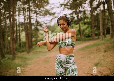 Hübsche junge Frau Stretching und atmen frische Luft in der Mitte des Waldes beim Training Stockfoto