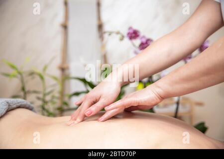 Junge Frau, die sich bei einer Rückenmassage im Spa-Center entspannt Stockfoto