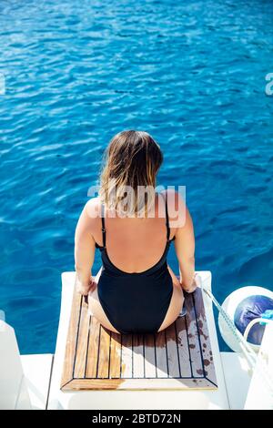 Rückansicht bei junger Frau, die sich an sonnigen Tagen auf der Yacht auf dem Meer entspannt Stockfoto