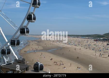 Die Leute reiten auf einem Riesenrad, während Strandgänger am 21. Mai 2020 in Den Haag die Sonne am Strand von Scheveningen genießen. Kredit: Yuriko Nakao/AFLO/Alamy Live News Stockfoto