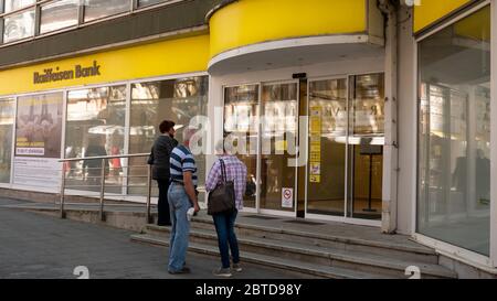 Gyor Ungarn 05 22 2020: Menschen in Schutzmasken warten darauf, in eine Raiffeisenbank zu gelangen. Die Maske wird wegen des Coronavirus getragen. Stockfoto