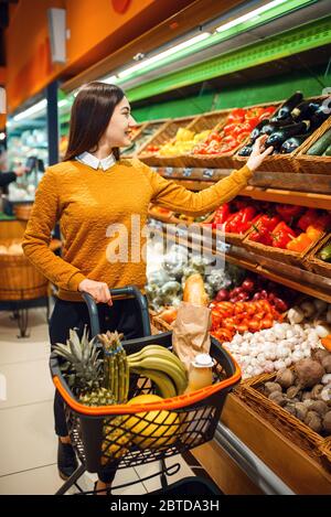 Junge Frau mit Korb im Lebensmittelgeschäft Stockfoto
