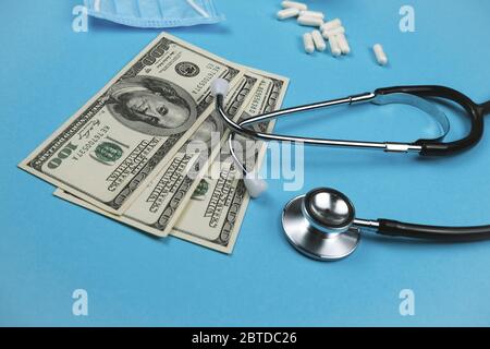 Stethoskop, Maske, verstreute Pillen und Geld auf dem blauen Hintergrund. Konzept der Medizin. Online-Arzt. Stockfoto