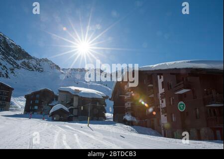 Wintersonne im Skigebiet Belle Plagne hoch in den Savoyer alpen, Frankreich. Eine Skipiste führt durch das Dorfzentrum. Stockfoto