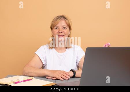 Ältere ältere Frau mit drahtlosen Laptop-Apps Surfen Internet sitzen am Tisch, lächelnd mittleren Alters Großmutter arbeitet entfernt am Computer Stockfoto