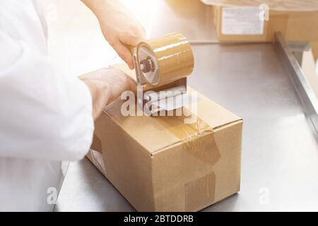 Arbeiter packt Kartonagen mit Fertigwaren in der Fabrik. Stockfoto