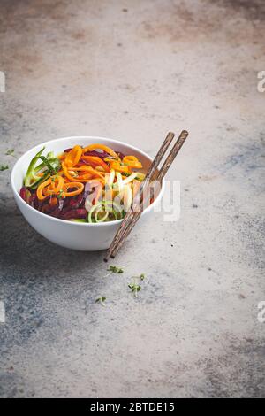 Gemüsennudeln - Zucchini, Rüben und Möhren in einer Schüssel, dunkler Hintergrund. Rohes veganes Essen. Stockfoto