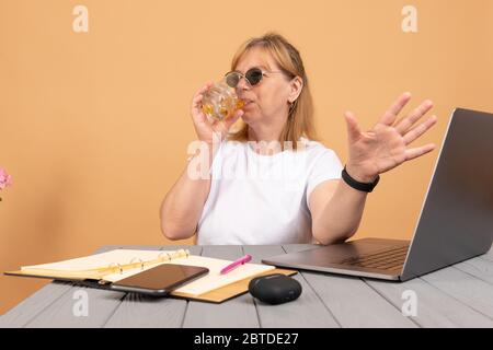 Betrunkene ältere Frau trinkt Whisky und arbeitet an ihrem Computer Stockfoto