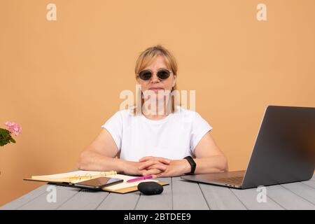 Porträt von glücklich selbstbewusst Senior blonde-haarige Geschäftsfrau in Brille sitzen am Schreibtisch Blick auf Kamera lächelnd Stockfoto