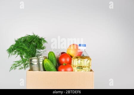 Spendenbox mit Lebensmitteln, offene Karteikarte mit Öl, Äpfeln, Gurken, Tomaten und Konserven. Copyspace. Stockfoto