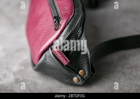 Taillentasche aus dunkelrotem Leder, Banane auf grauem Hintergrund. Handgefertigt Stockfoto