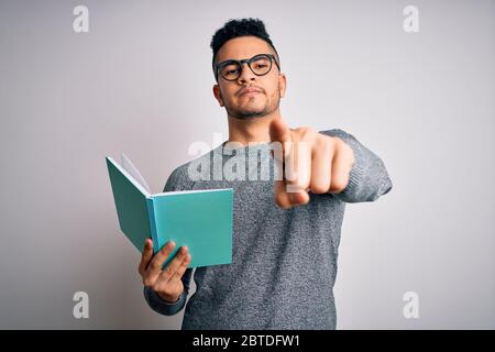 Junge schöne smart Student Mann Lesebuch über isolierten weißen Hintergrund zeigt mit Finger auf die Kamera und zu Ihnen, Handzeichen, positiv und Co Stockfoto