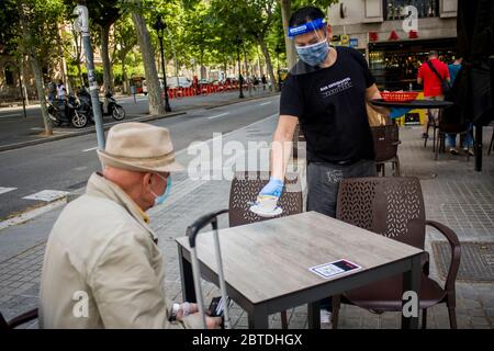 Barcelona, Spanien. Mai 2020. 25. Mai 2020, Barcelona, Katalonien, Spanien: Ein Kellner mit Gesichtsmaske und schützendem Gesichtsschutz serviert einem Kunden in einer Bar in Barcelona einen Kaffee. Barcelona und seine Metropolregion treten in Phase 1 des Coronavirus-Sperrungsprozesses ein ab diesem Montag können die Terrassen von Bars und Restaurants nach 2 Monaten der Schließung bis zur Hälfte ihrer Kapazität geöffnet werden. Quelle: Jordi Boixareu/Alamy Live News Stockfoto