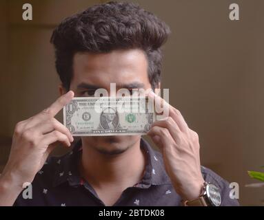 Junger Mann hält Dollarschein vor seinem Gesicht . ein Dollar. Stockfoto