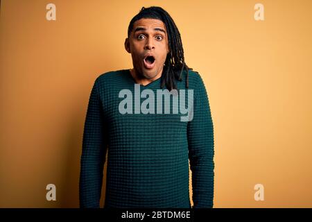 Junge gut aussehende afro amerikanischen Mann mit Dreadlocks tragen grünen lässigen Pullover Angst und schockiert mit überraschenden Ausdruck, Angst und aufgeregt fa Stockfoto