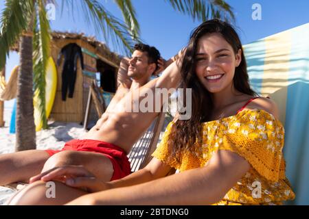 Kaukasisches Paar auf Liegestühlen am Strand Stockfoto