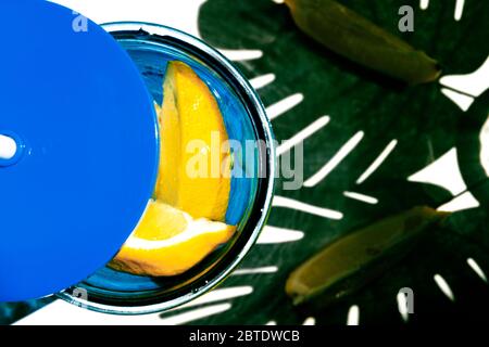 Blick von oben auf ein Glas Limonade mit Zitronenscheiben und einem Schatten von Palmblättern. Hallo Sommer Konzept. Stockfoto