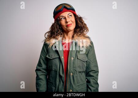 Mittlere Alter Skifahrer Frau trägt Schnee Sportbekleidung und Skibrille über weißem Hintergrund lächelnd Blick auf die Seite und starrte weg denken. Stockfoto