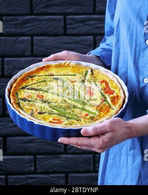 Eine Frau hält frisch gebackene Quiche mit Lachs Spargel Käsefüllung, close-up Stockfoto