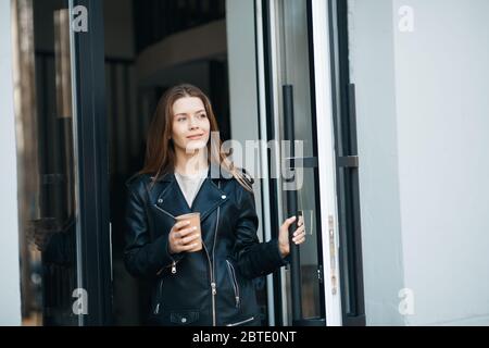 Junge Brünette Frau gehen im Freien mit einer Tasse Kaffee Stockfoto