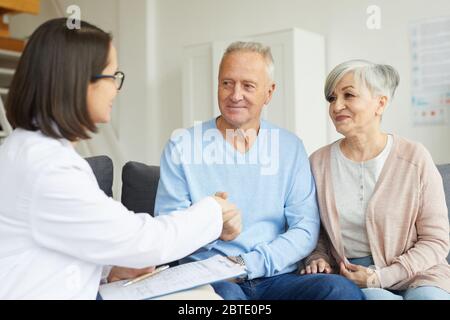 Porträt von lächelnden älteren Paar Hände schütteln mit Ärztin während des Besuchs Privatklinik Stockfoto