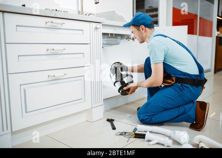 Männlicher Klempner in Uniform, der Enteigner installiert Stockfoto